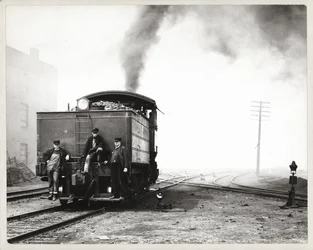 Three Men on the Back of a Switch Engine in an Unidentified Rail Yard